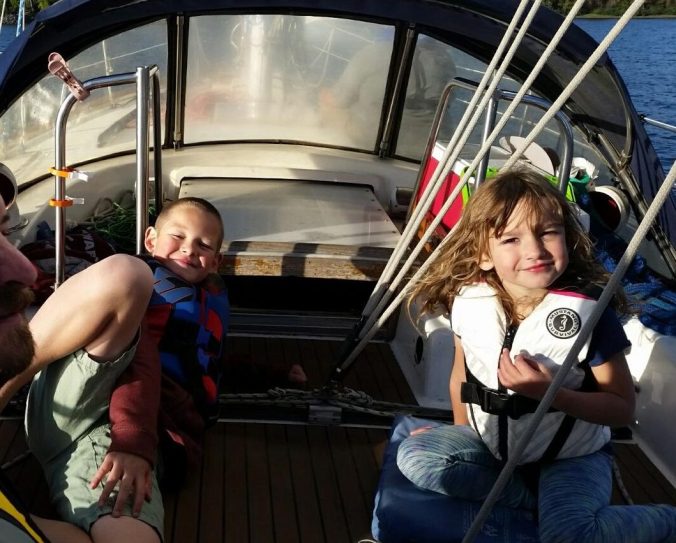 A boy and a girl in the cockpit of a sailboat under sail.