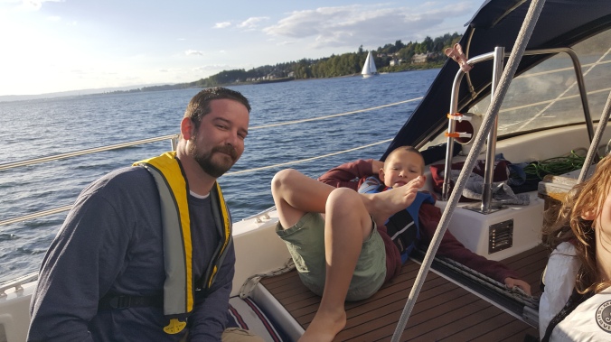 A man and a boy relaxing in the cockpit of a sailboat while sailing