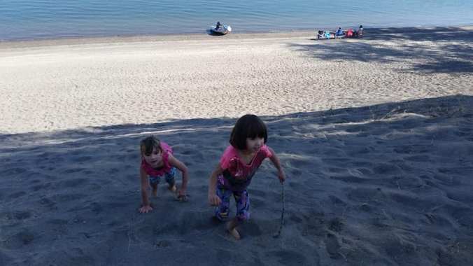 Two girls playing in the sand on a large sand dune on the Columbia River