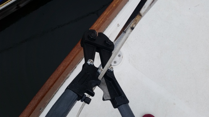Using bolt or cable cutters to cut the old rusty lifelines off our sailboat during replacement