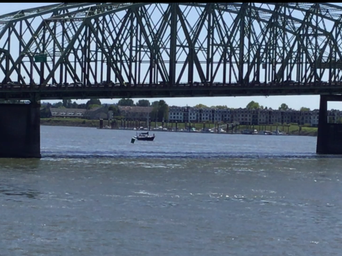 sailboat passing under the I5 bridge separating Washington and Oregon